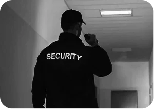 Security officer holding a radio while patrolling a hallway, representing active monitoring and safety.